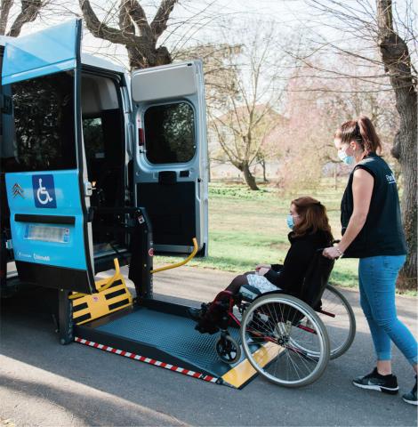 Accompagnant aidant une personne en fauteuil roulant à accéder au véhicule